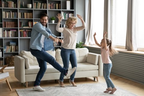 Little girl dancing at home with father and grandmother