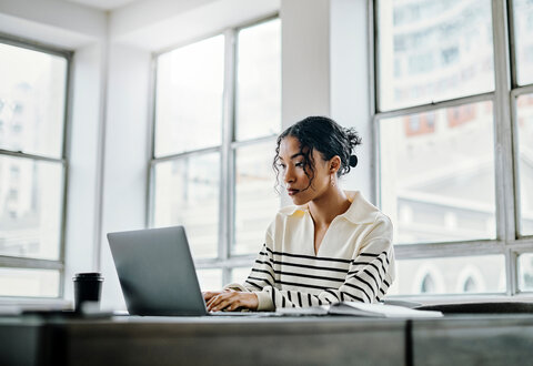 Woman typing on a laptop.